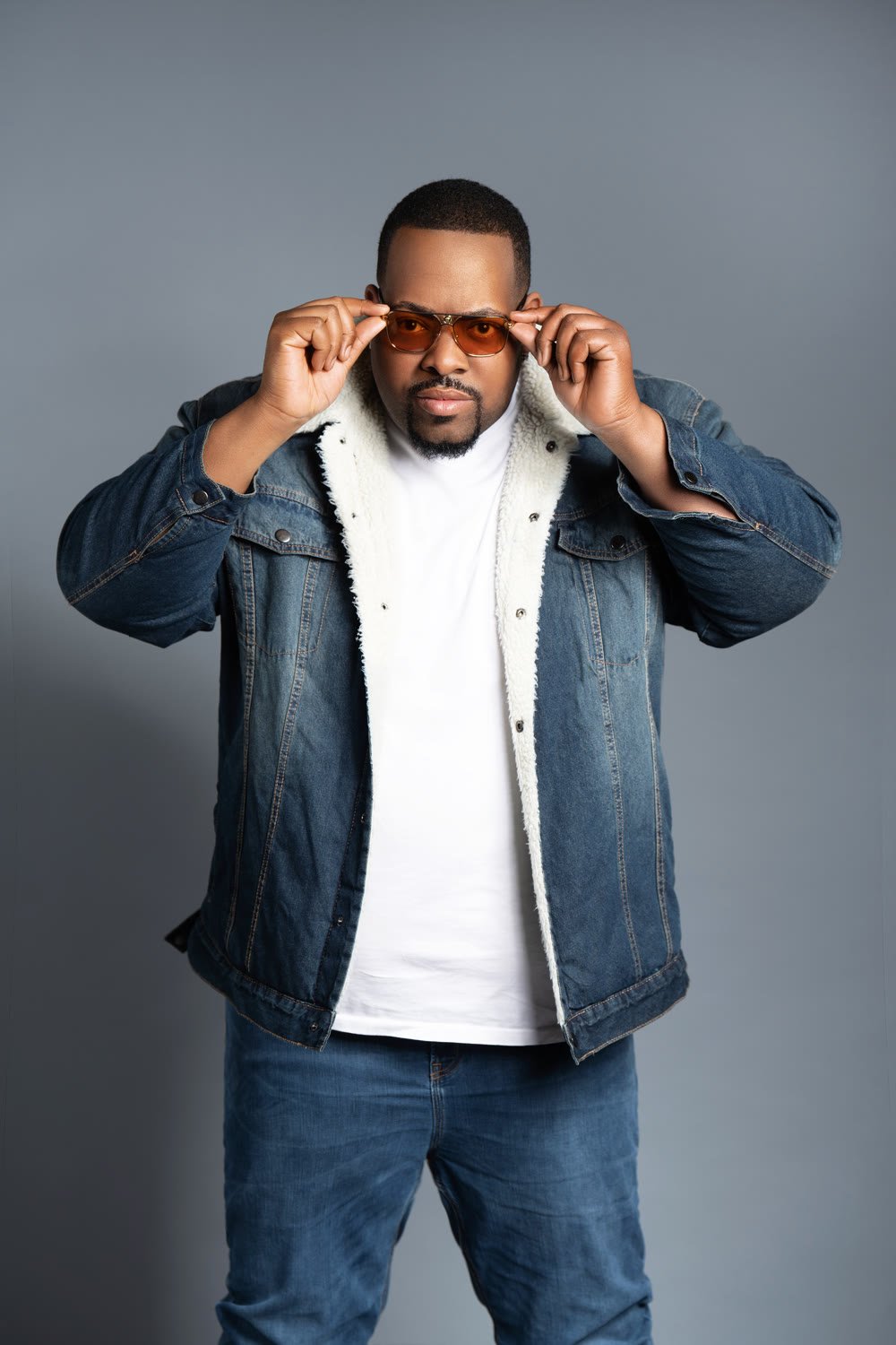 Prince Charm adjusting his amber sunglasses, denim jacket